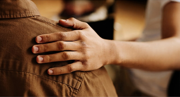 a hand touching a person's shoulder